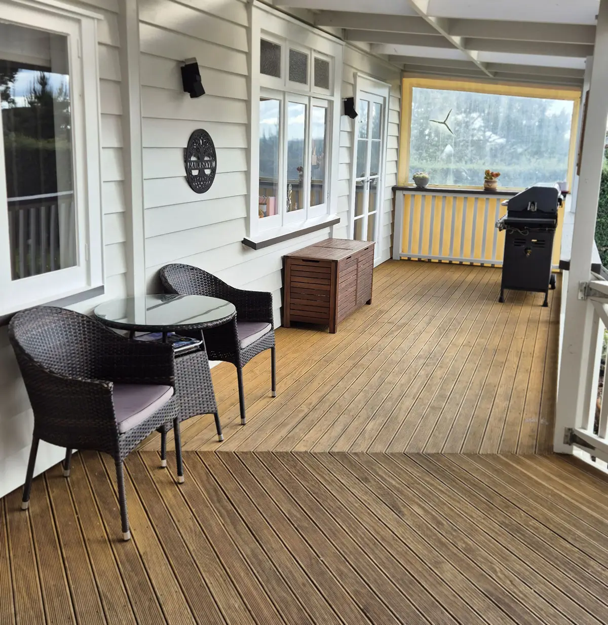 An outdoor covered deck area, with exterior of house freshly painted