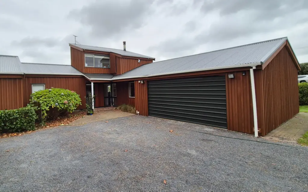 a large house in a rural setting with freshly-painted brown wooden exterior