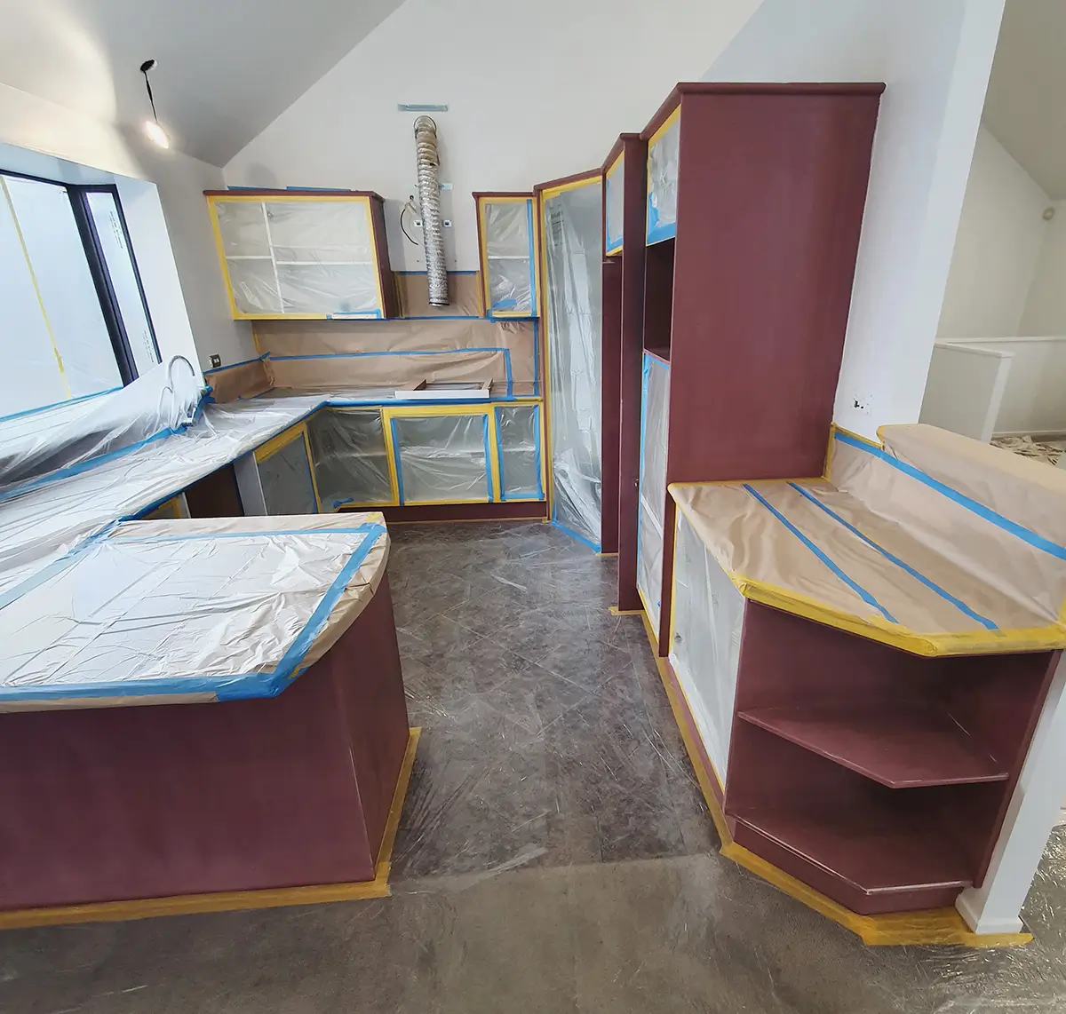 A kitchen prepped for painting. All surfaces to be protected are covered securely.