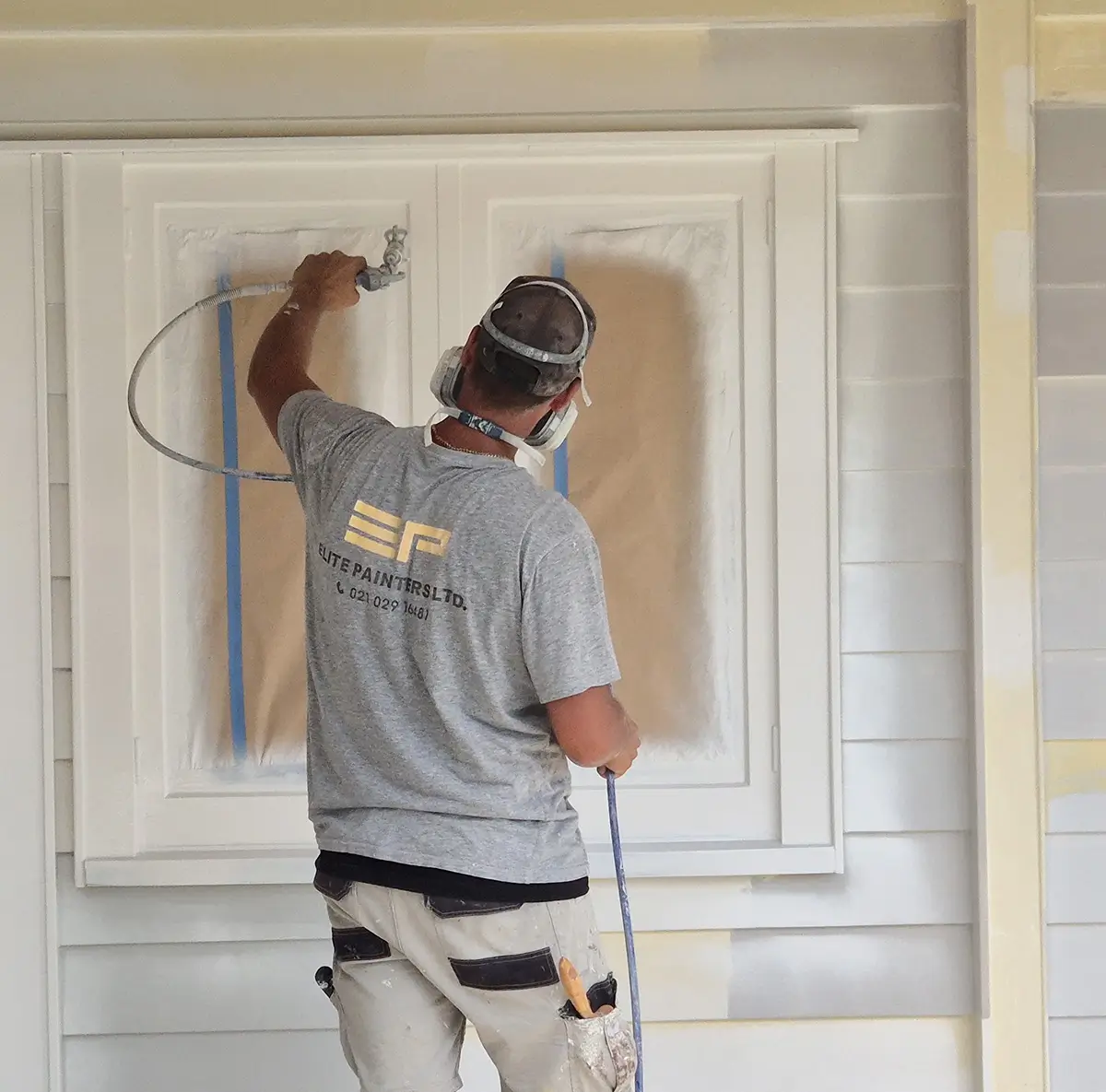 An Elite Painters team member preparing an exterior paint job